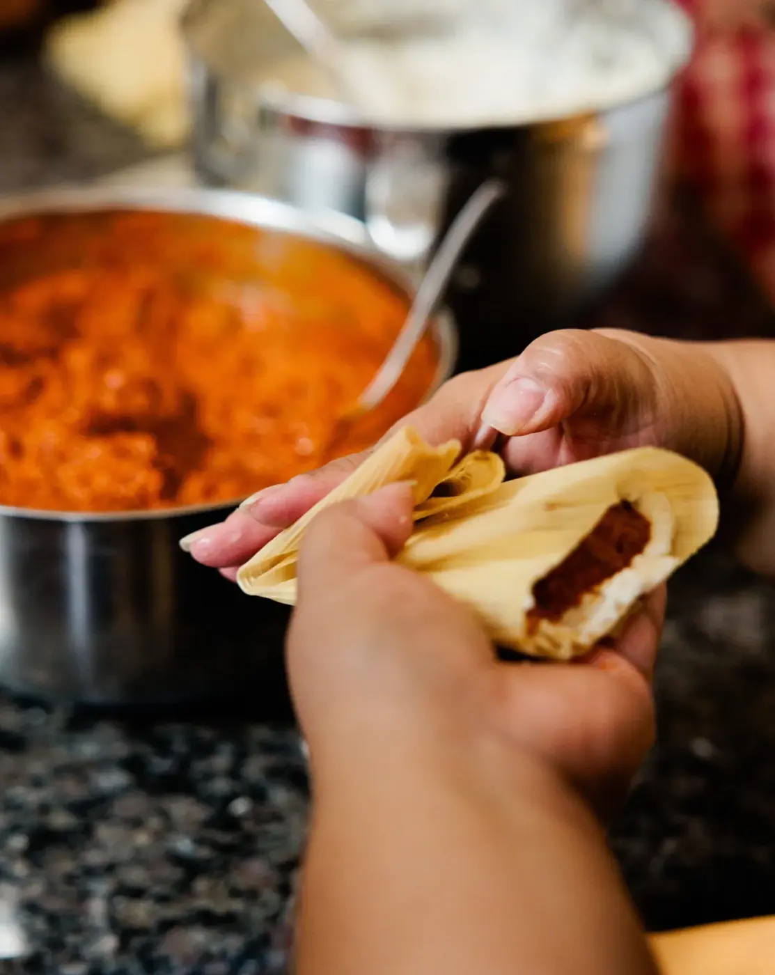 Hands filling a tamale